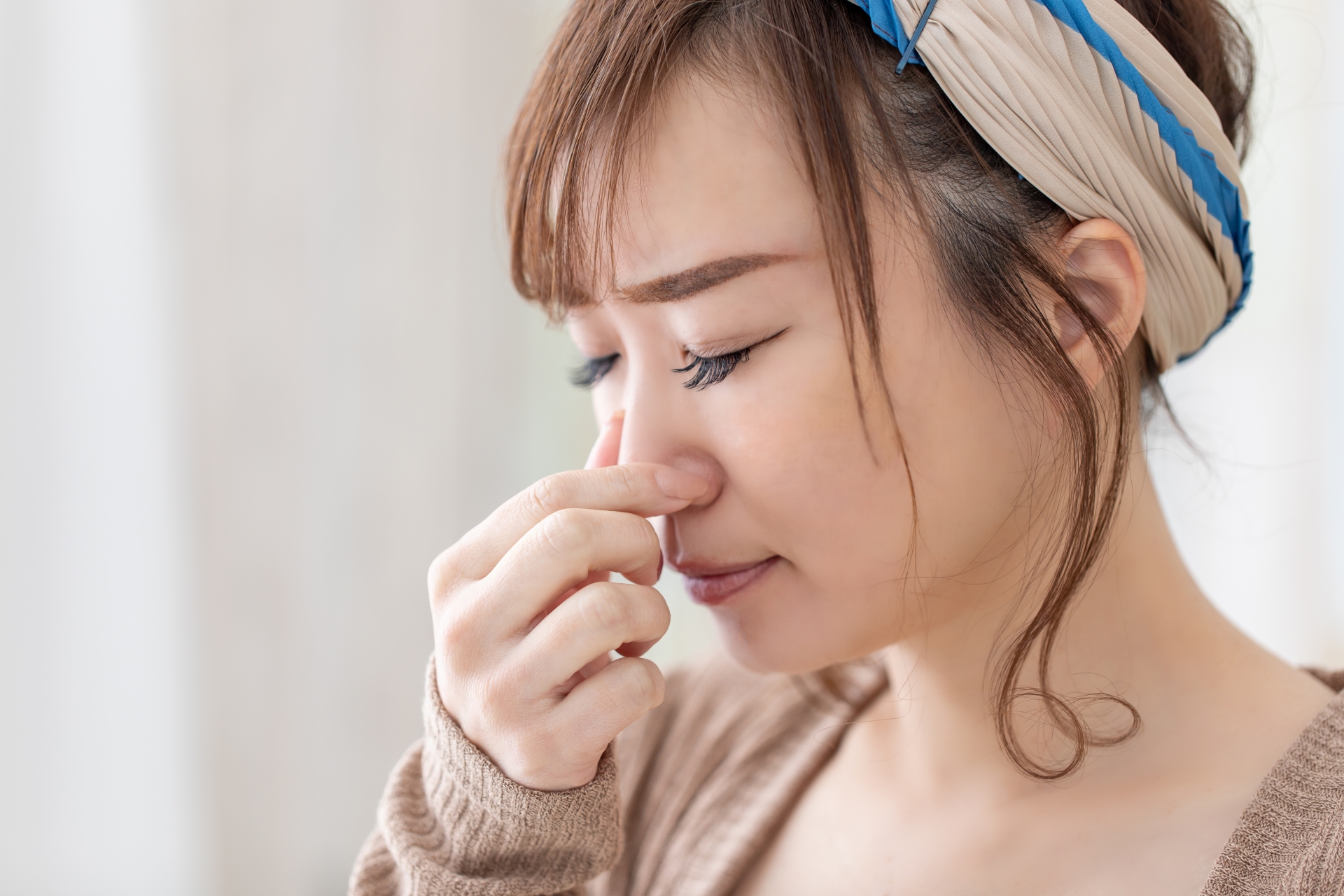 口元を手で覆い口臭を気にする女性