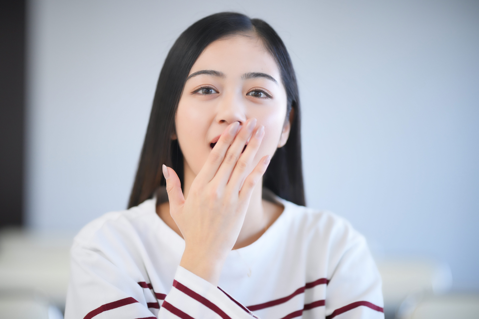 口元に手を添えて自分の口臭が気になる様子の女性