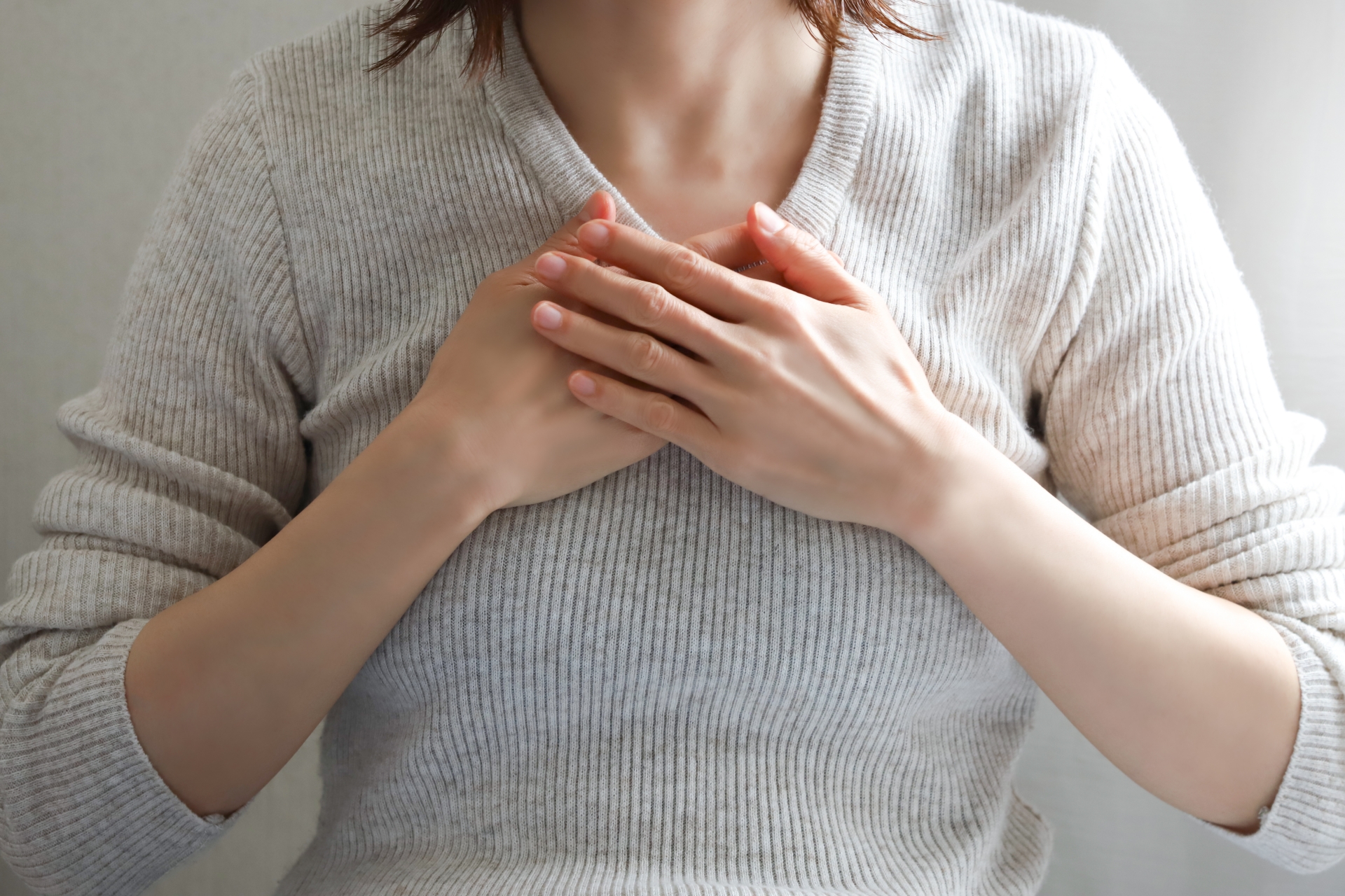 体調を気にして胸に手を当てる女性