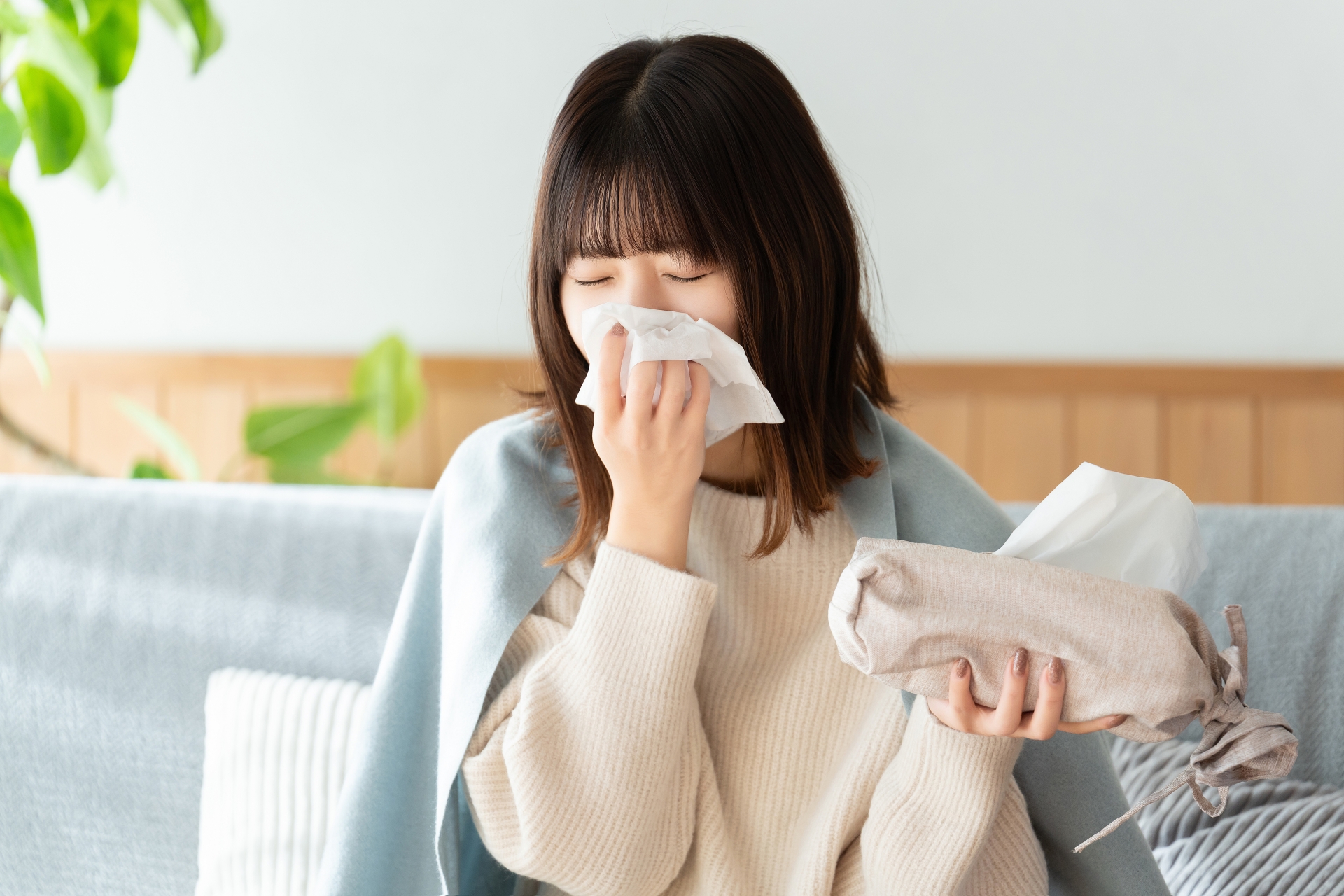 ブランケットにくるまりソファで安静にしている女性