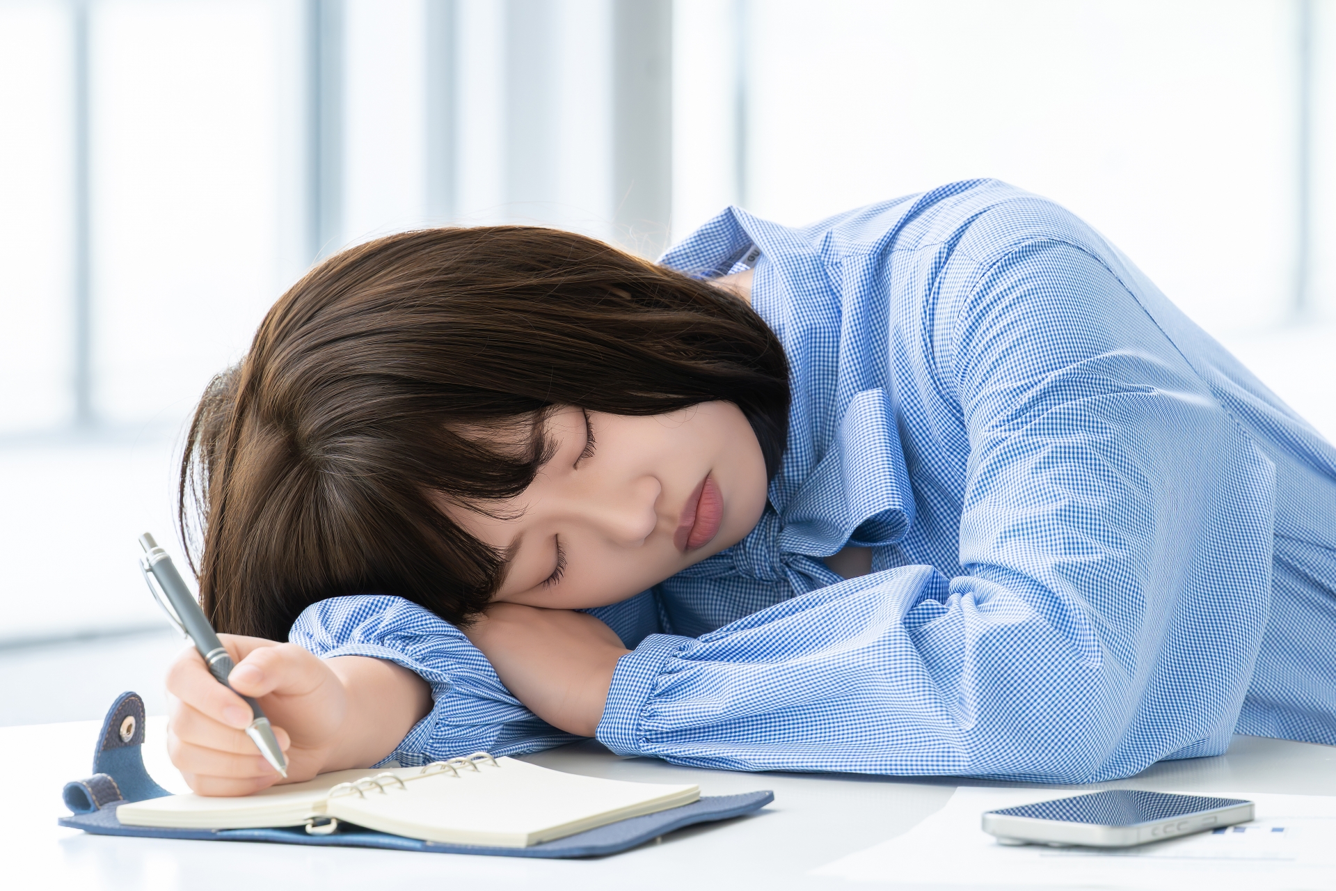 デスクでコンビニ弁当を食べながら仕事をしている様子