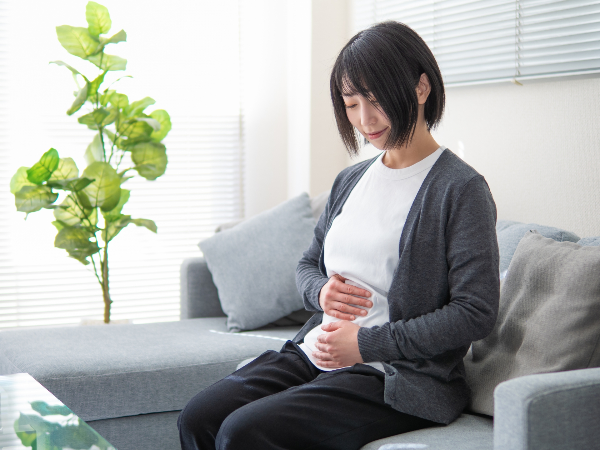 仰向けでお腹に手を当てて腸もみマッサージをする女性