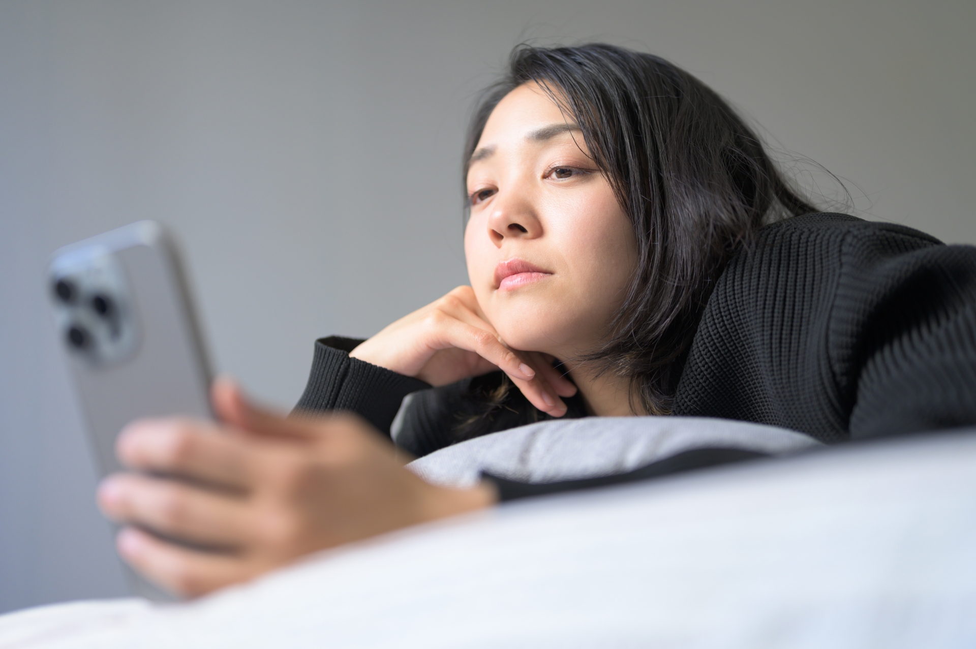 デスクで夜遅くまでスマホを見ながら過ごす女性