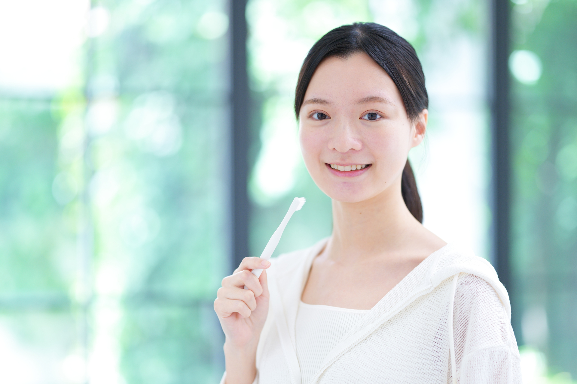 朝の洗面台で歯磨きをする女性