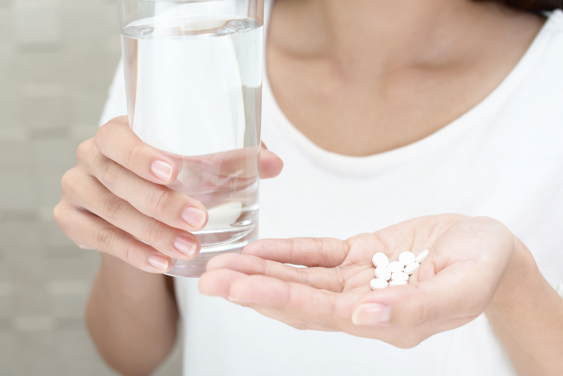 手のひらにサプリメントの錠剤を乗せている女性の手元クローズアップ