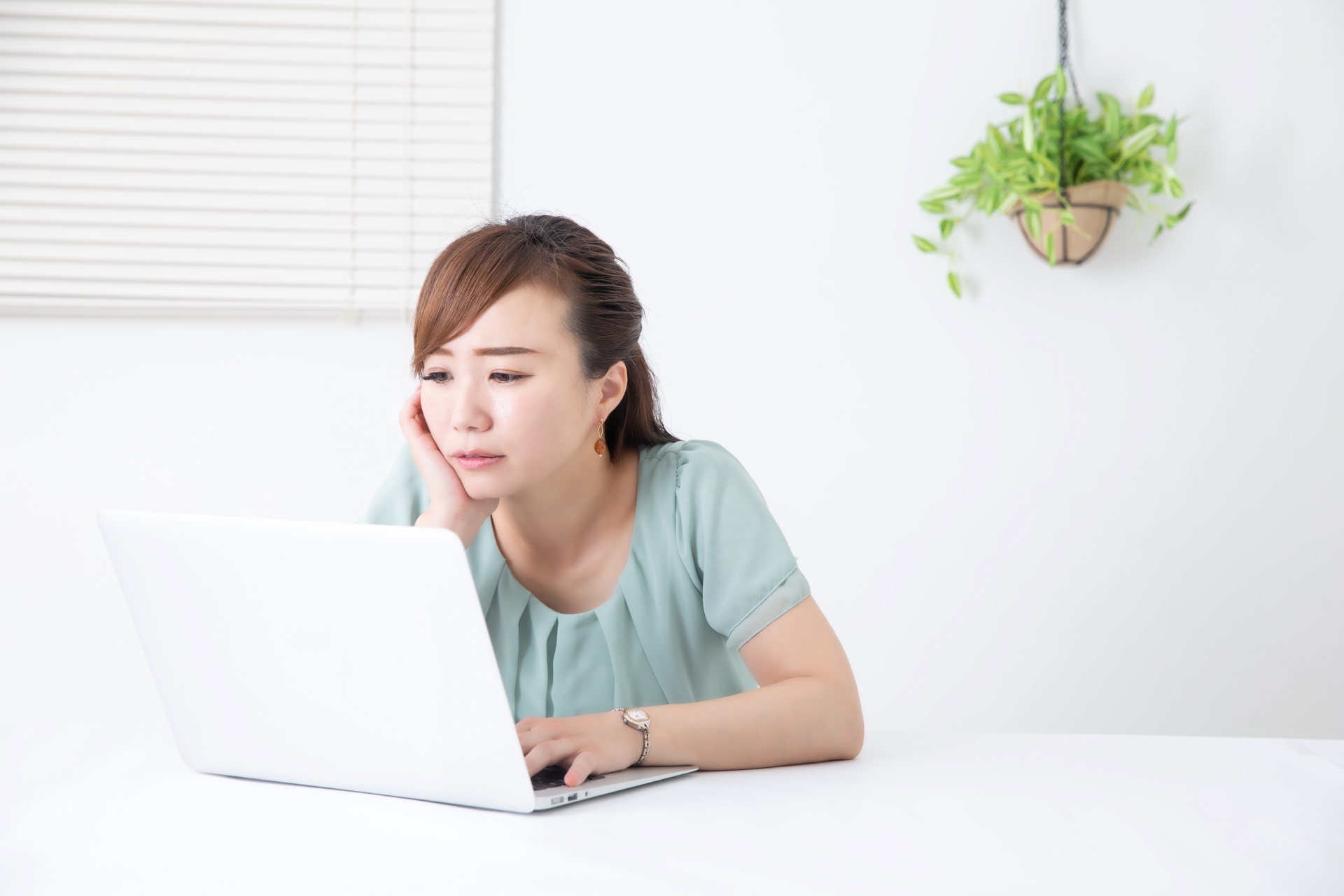 デスクで疲れた様子で頬杖をつく30〜40代の女性