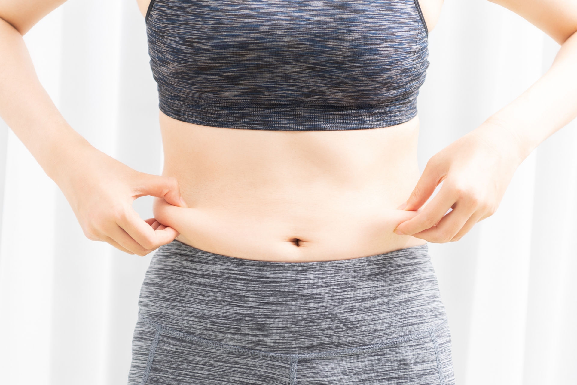 お腹周りの脂肪を気にする女性のイメージ