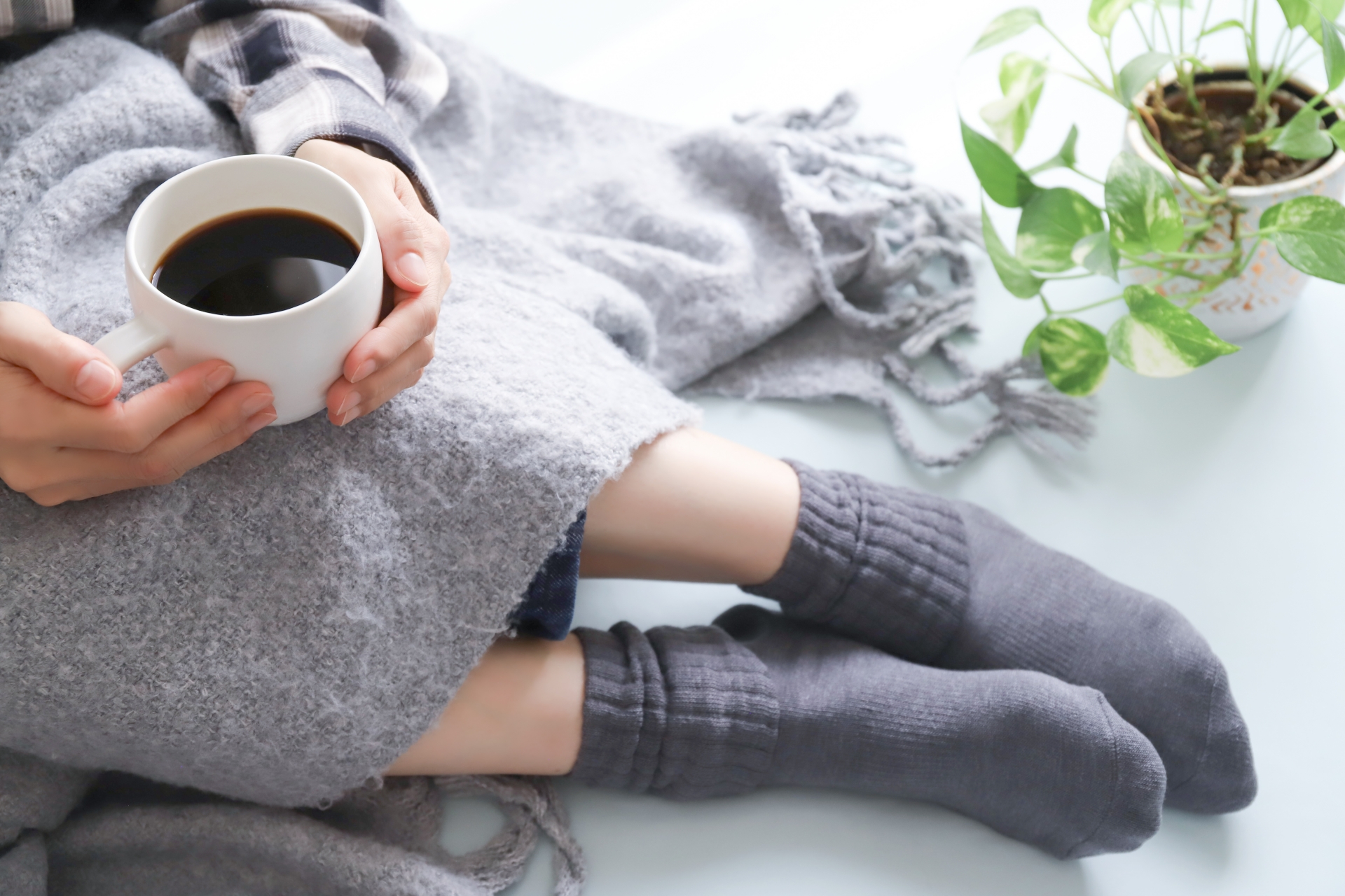 マグカップを両手で包むように持ち温かい飲み物を飲む女性