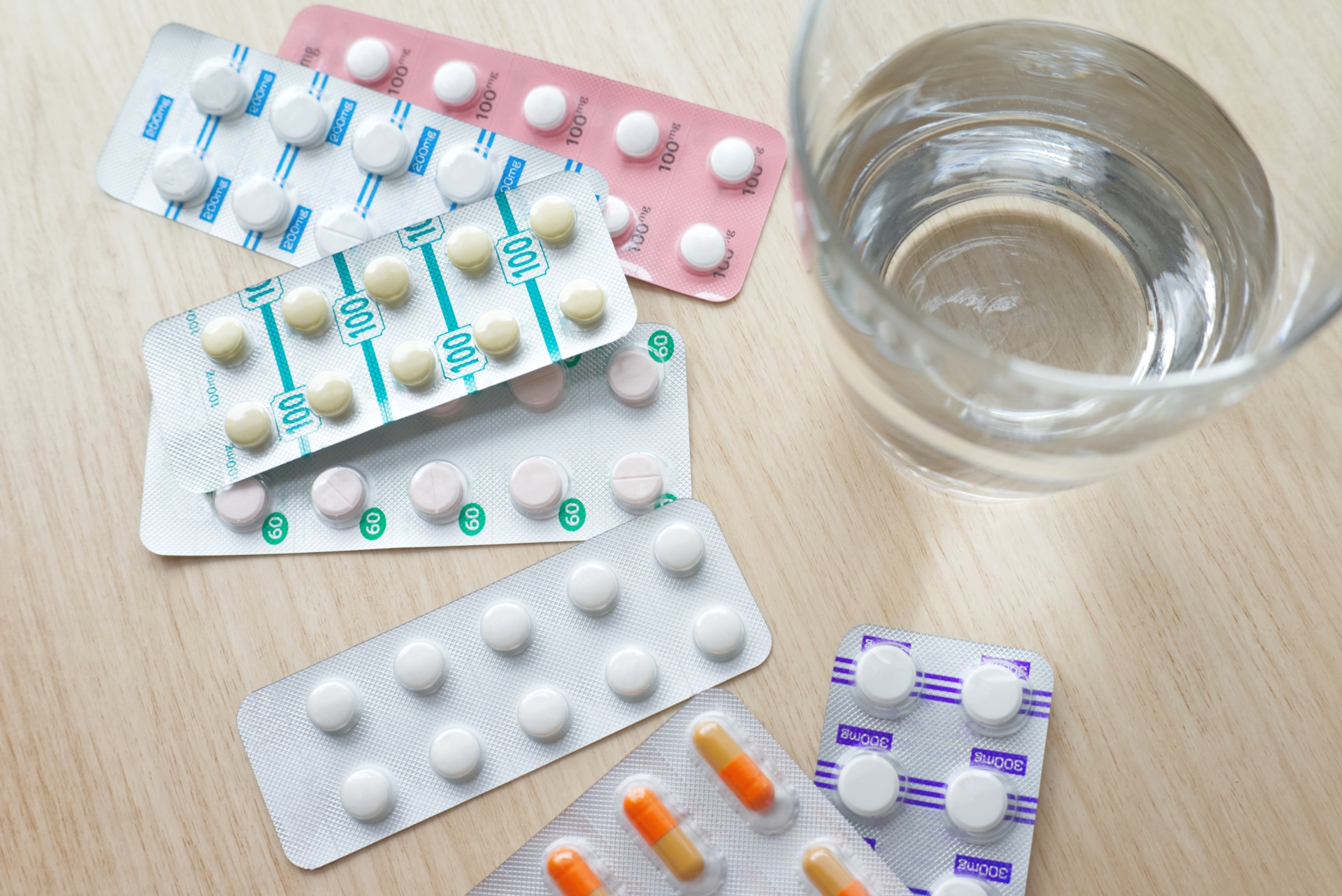 テーブルに置かれた体温計と薬と水の入ったコップ