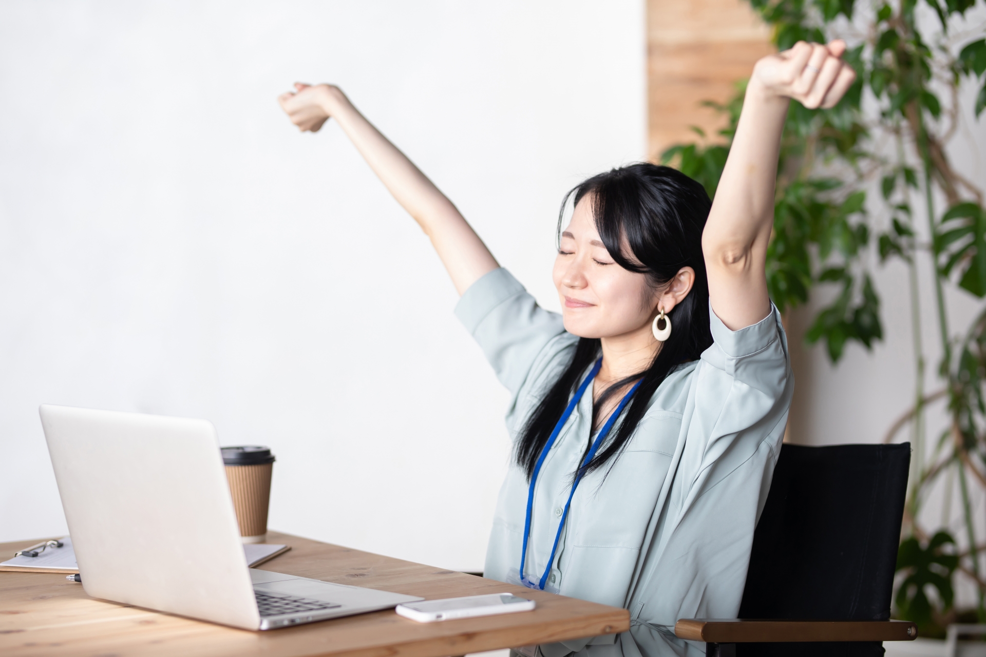 オフィスのデスクで目を閉じて深呼吸する女性