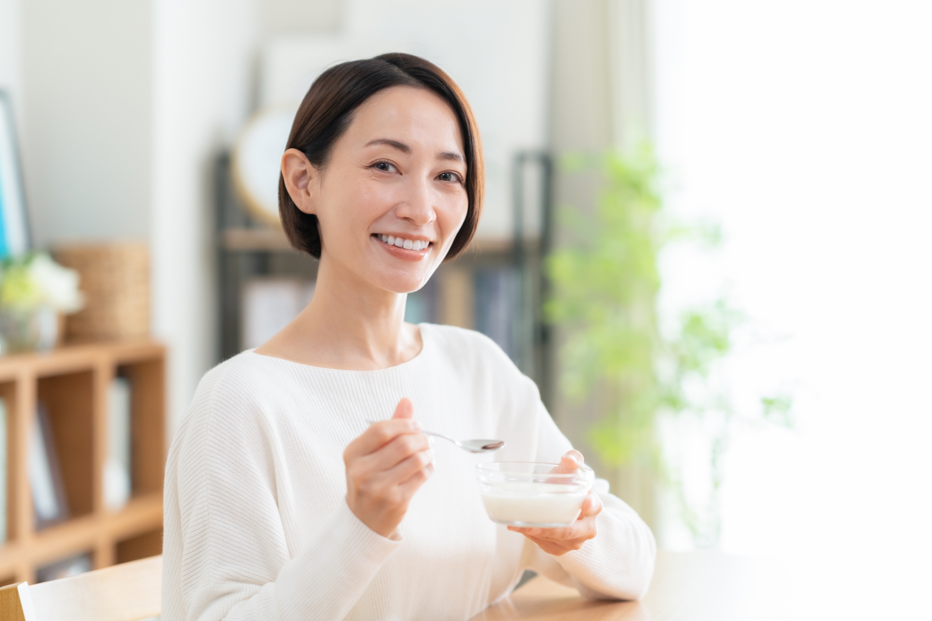 ヨーグルトと発酵食品が並んだ食卓と笑顔の女性