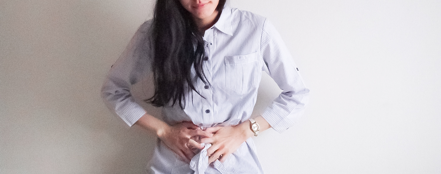 お腹に手を当てる女性｜胃からくる口臭と消化器系の不調のイメージ