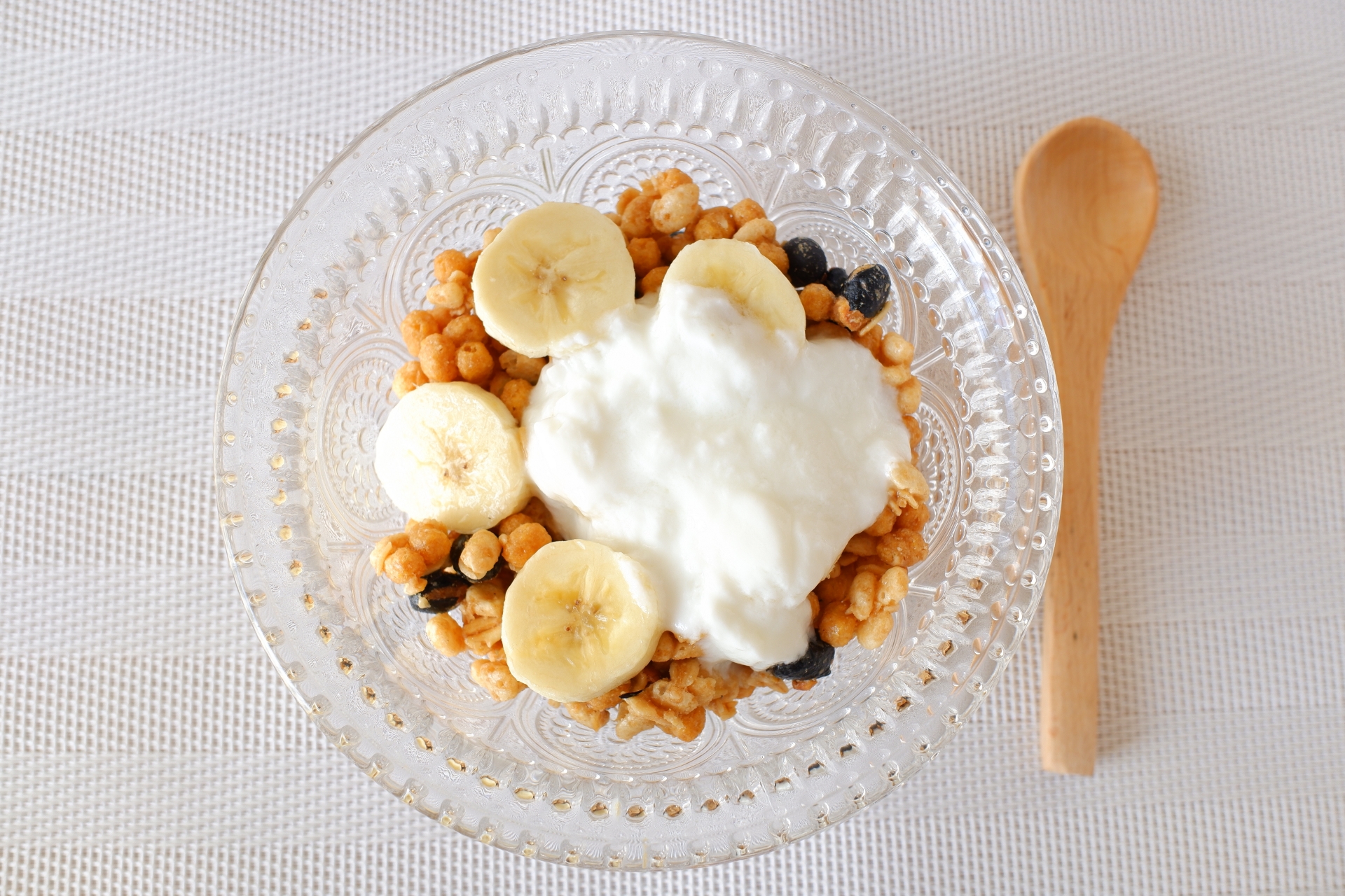 ヨーグルトにバナナを添えた朝食を食べようとする女性の手元