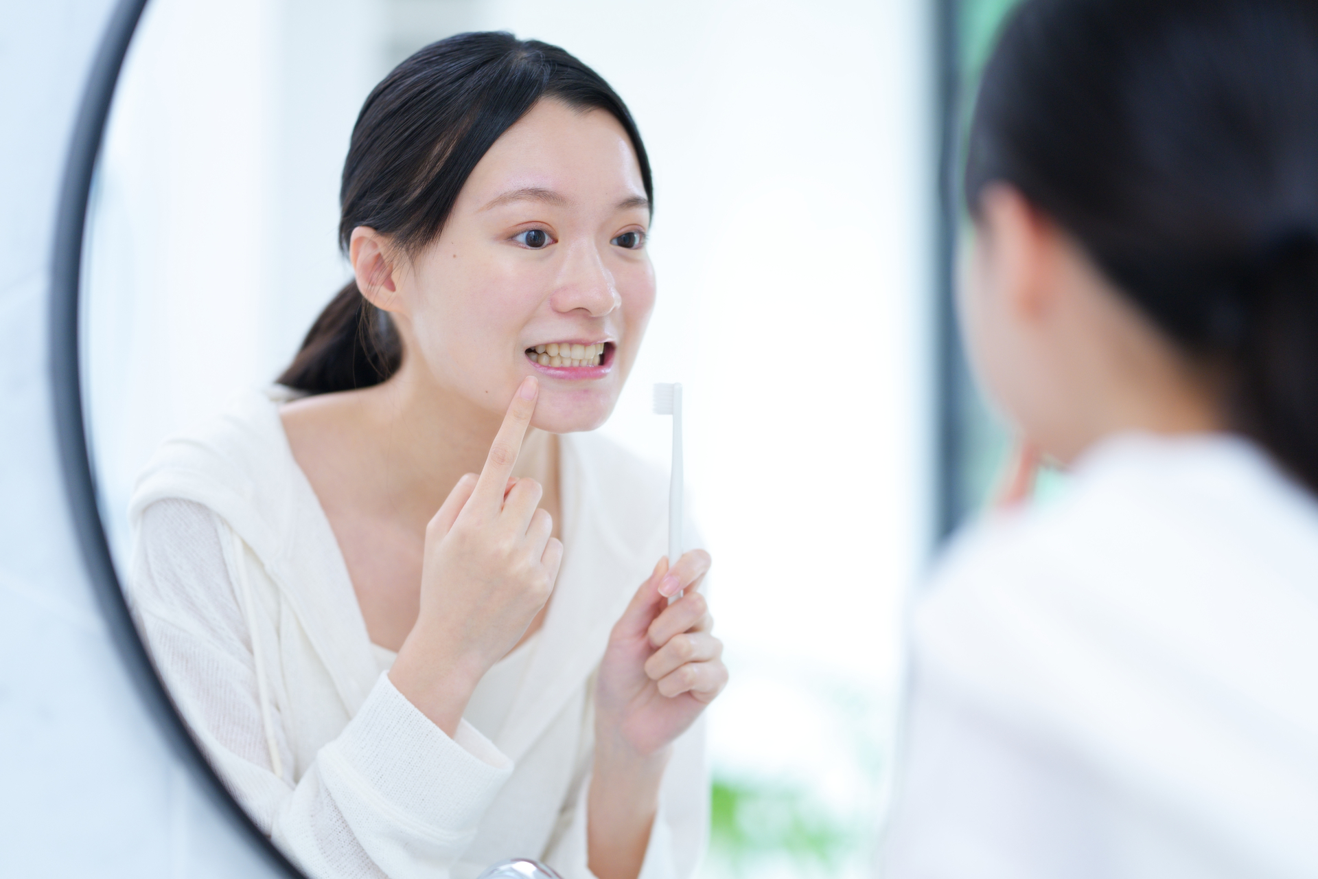 洗面台の鏡の前で口元を確認する女性｜口臭セルフチェックのイメージ