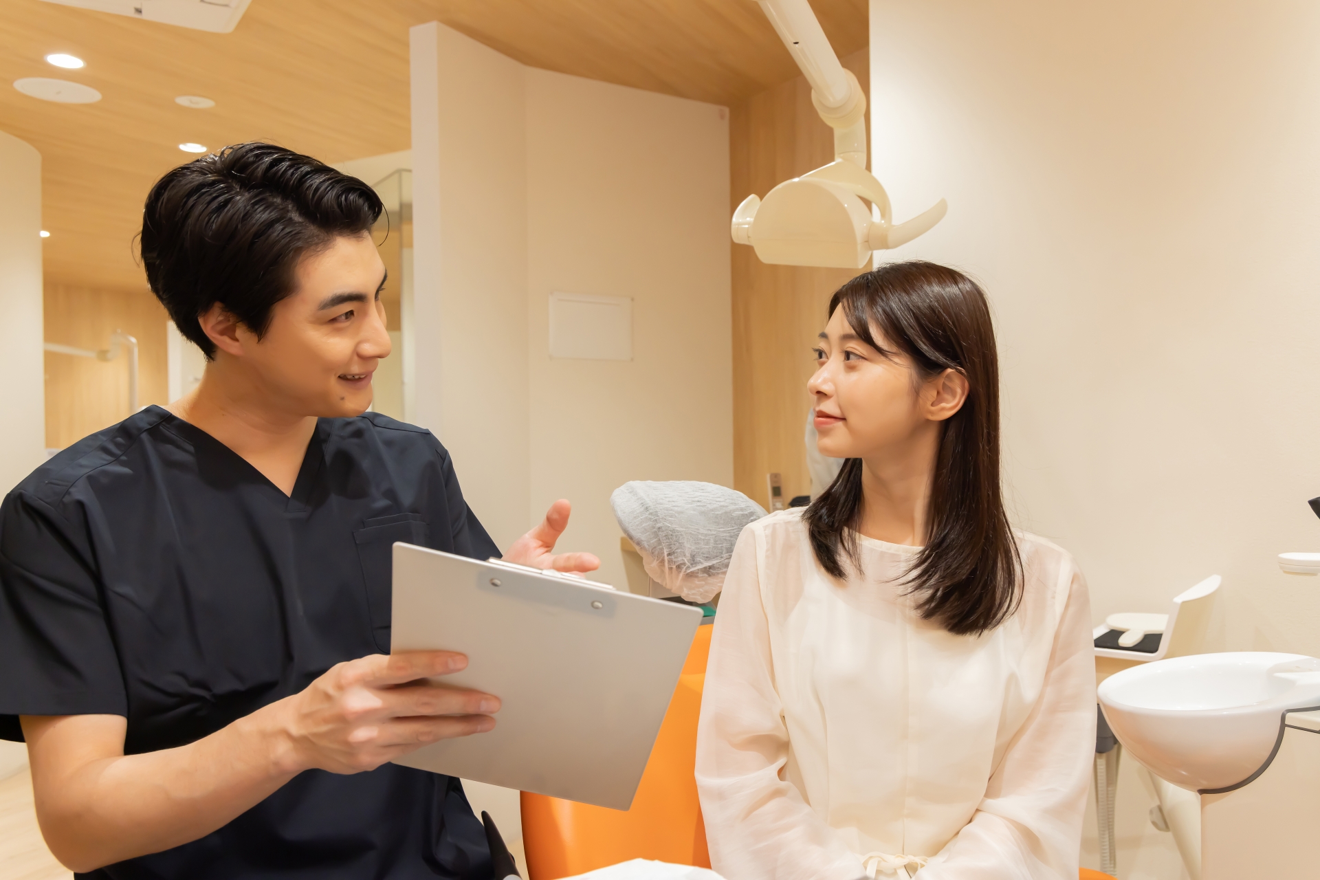 歯科医院の診察室で歯科医が患者に説明をしている様子