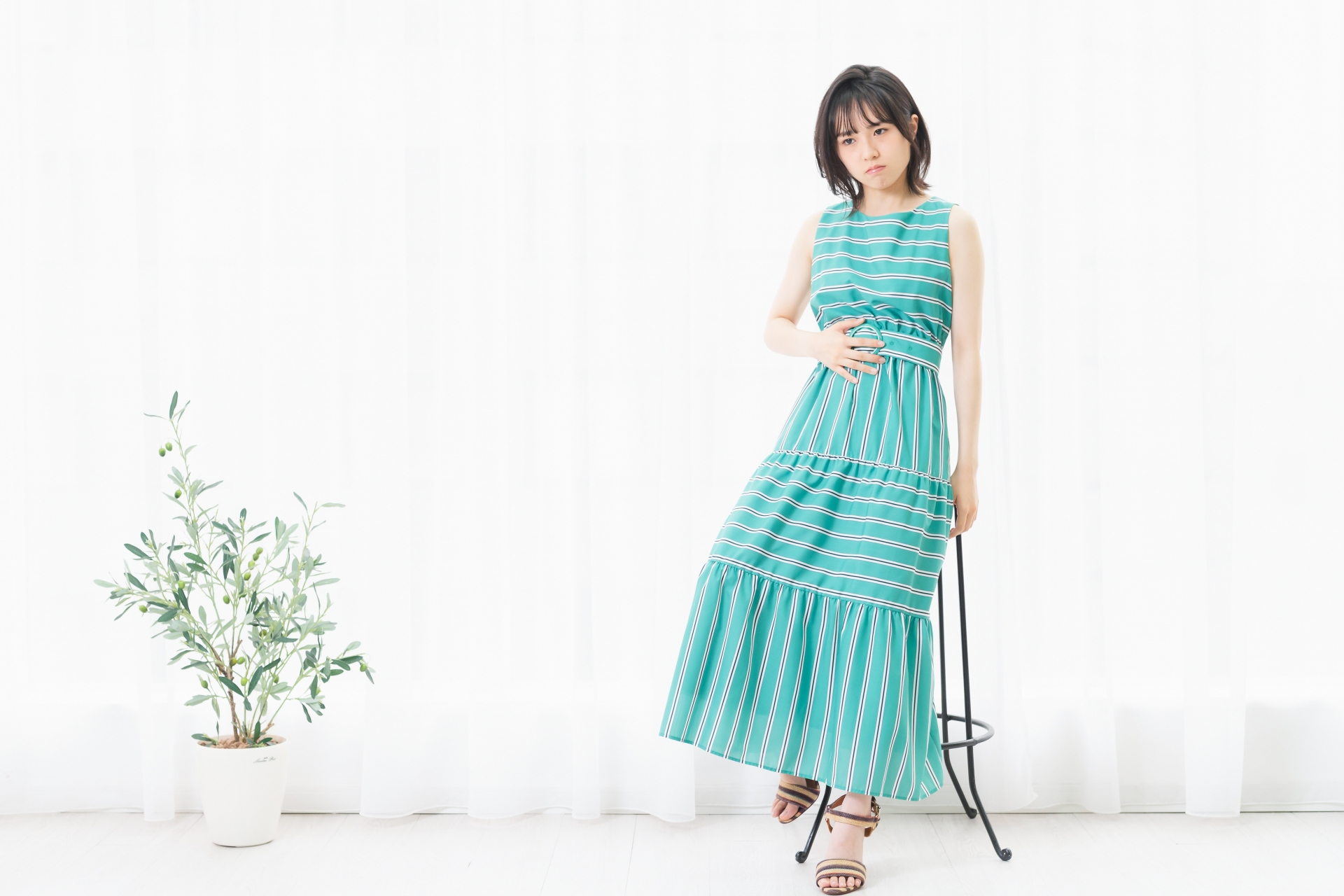 窓際の明るい部屋でお腹に手をあてて微笑む女性