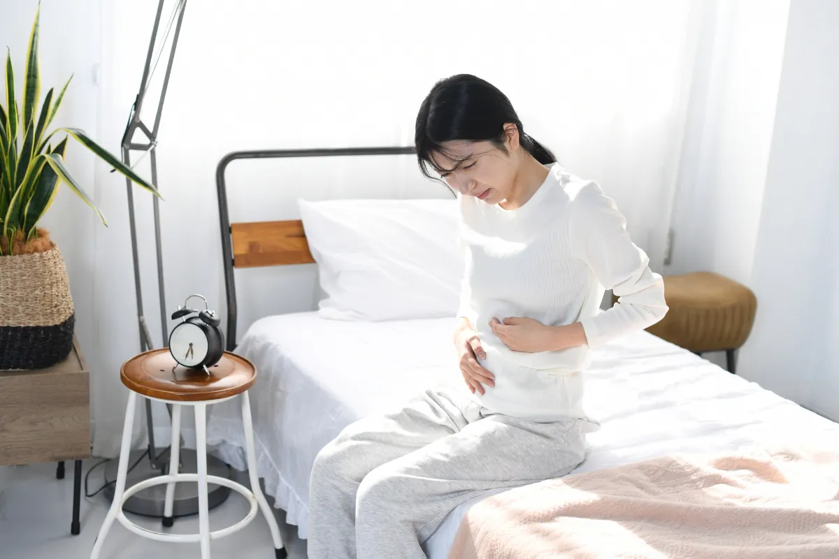 お腹を押さえてセルフチェックする女性