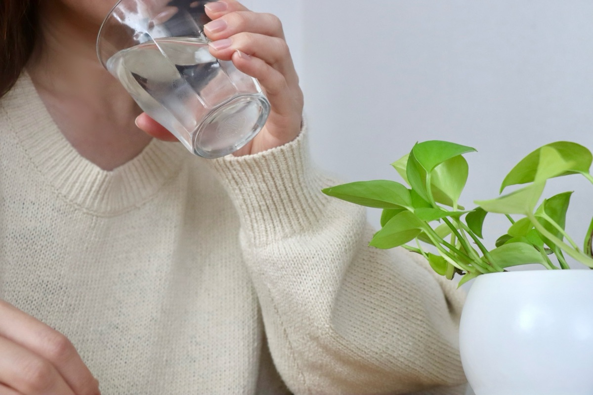 コップの水に手を伸ばす手元｜口の渇きを感じるドライマウスのイメージ