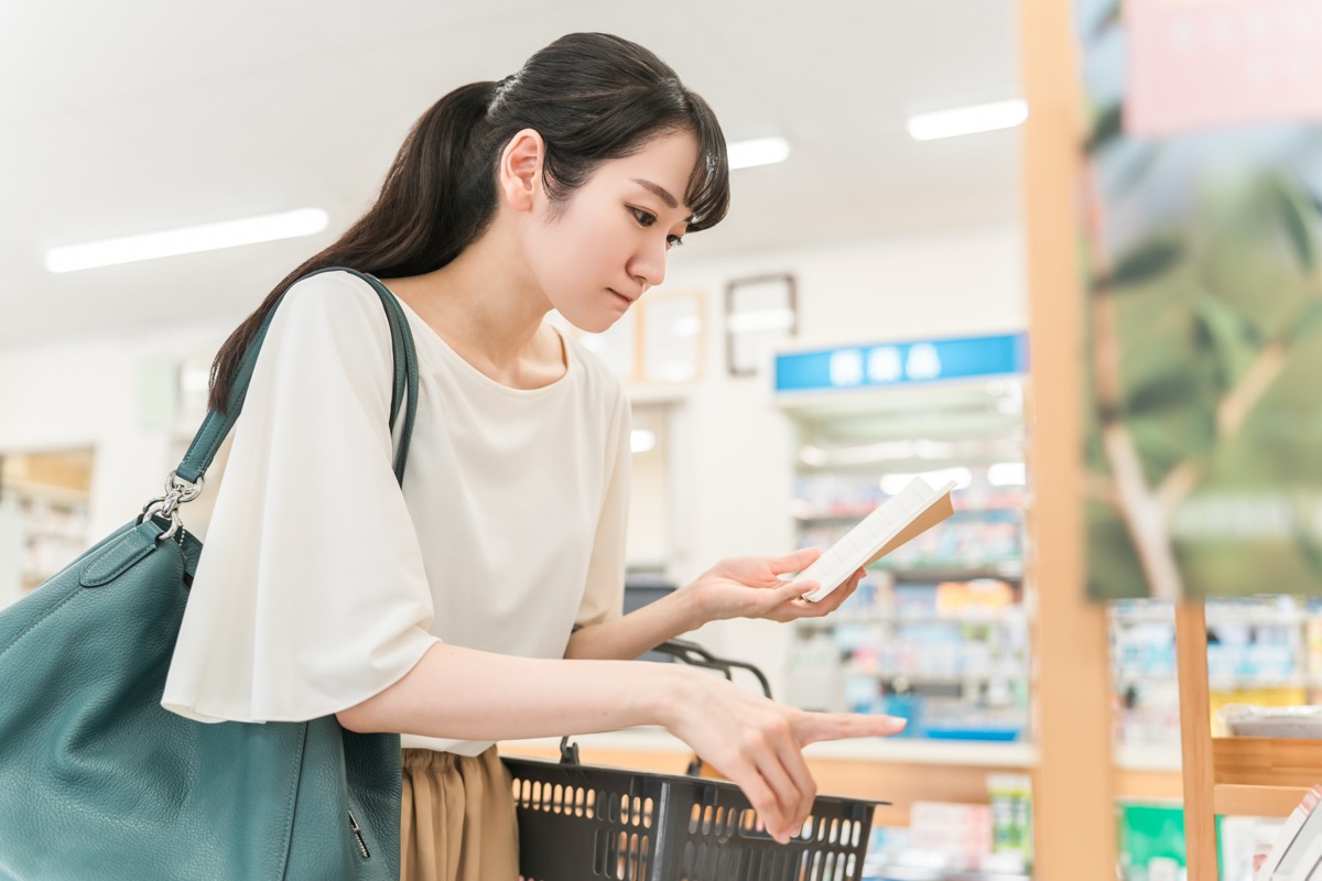 ドラッグストアの整腸剤コーナーで商品を手に取って見比べている女性