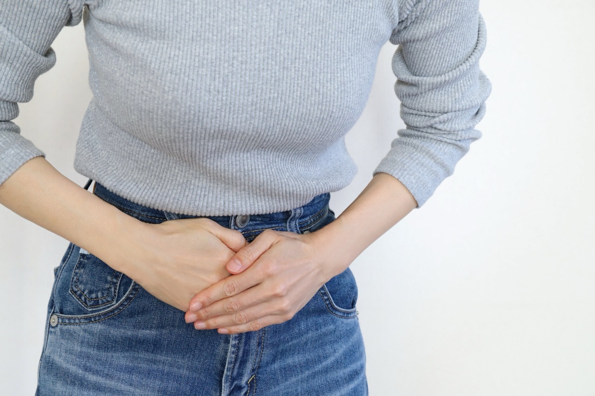 お腹の張りを気にして押さえる女性のイメージ