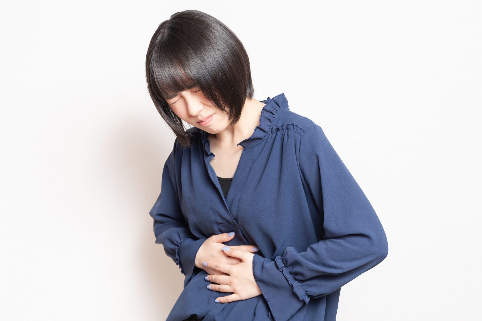 お腹に手を当てて体調を気づかう女性