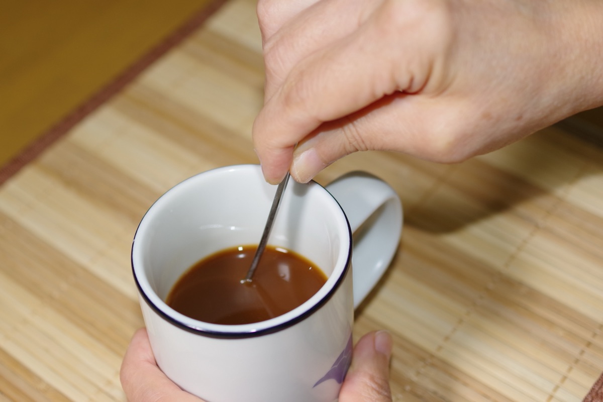 味噌汁やスープに粉末を混ぜ入れる女性のイメージ