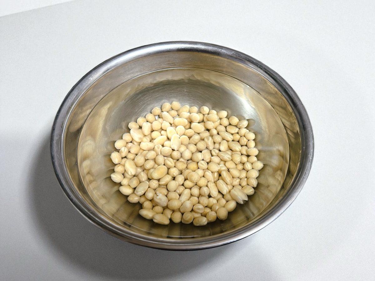 ボウルにたっぷりの水と大豆を入れて浸水させている様子のイメージ