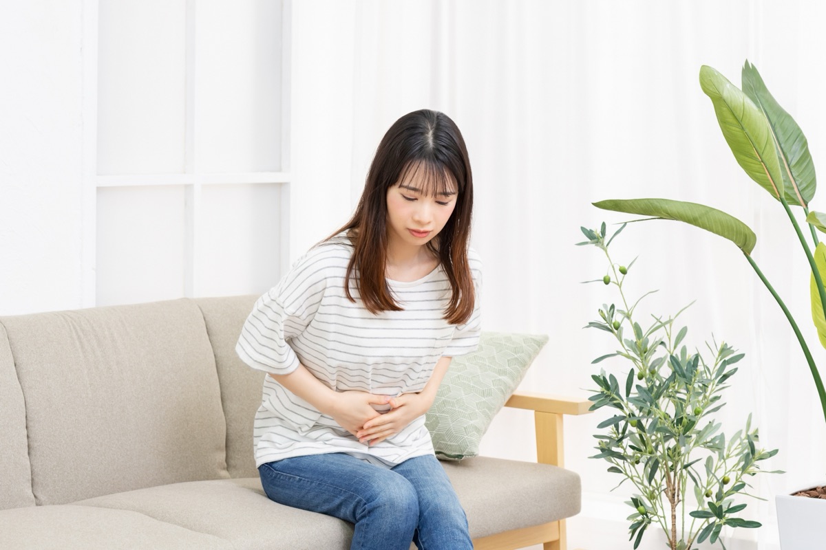 リビングのソファでお腹に手をあてている女性の自然な横姿