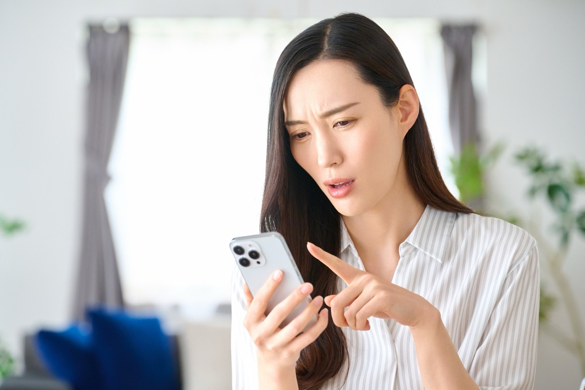 スマホの広告を見て冷静に考える女性のイメージ