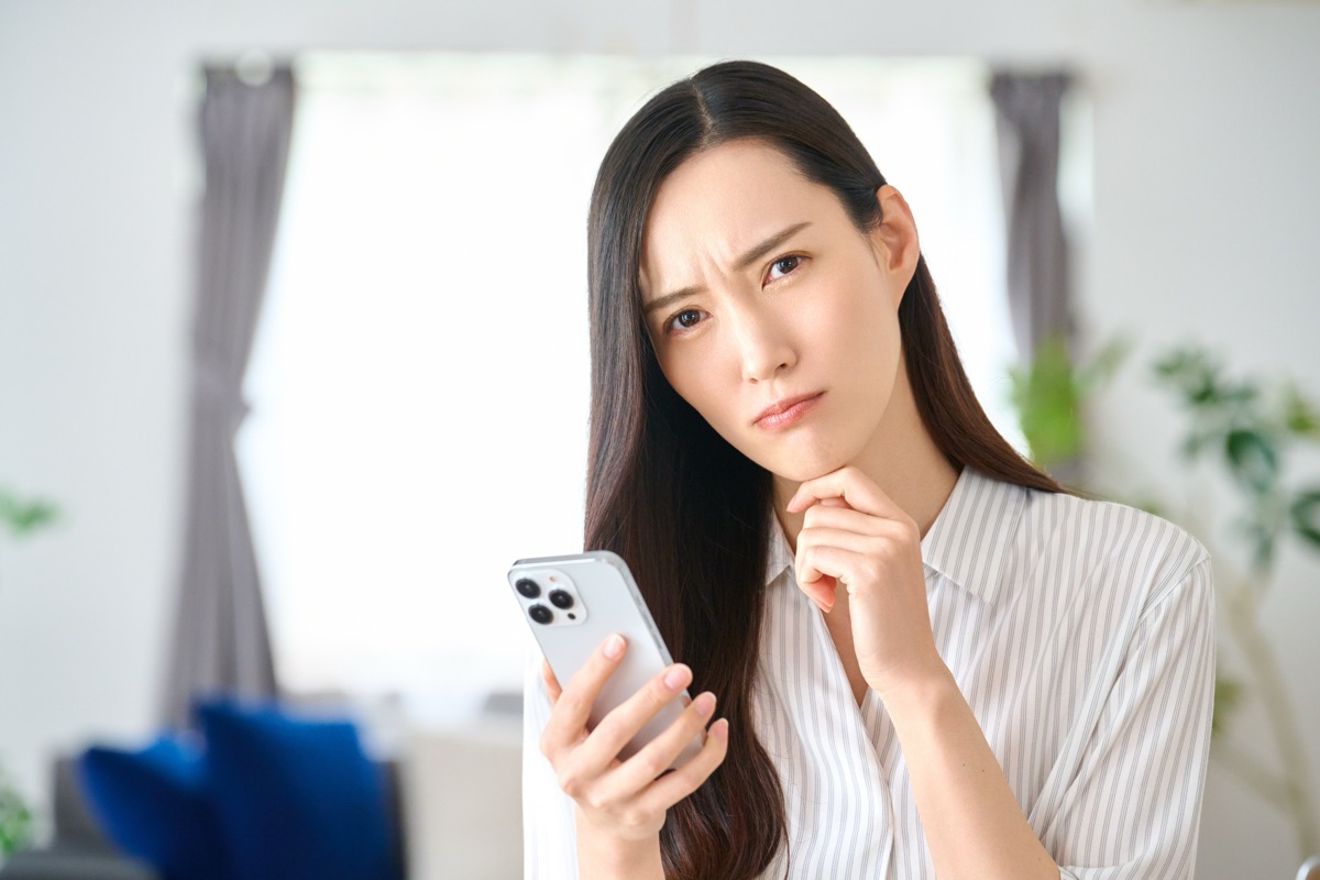 スマホの広告を見て冷静に考える女性のイメージ
