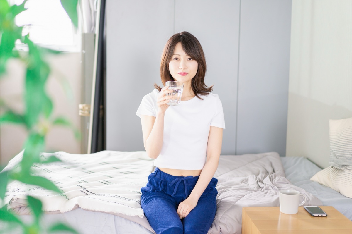起床後にコップの白湯を飲む女性のイメージ