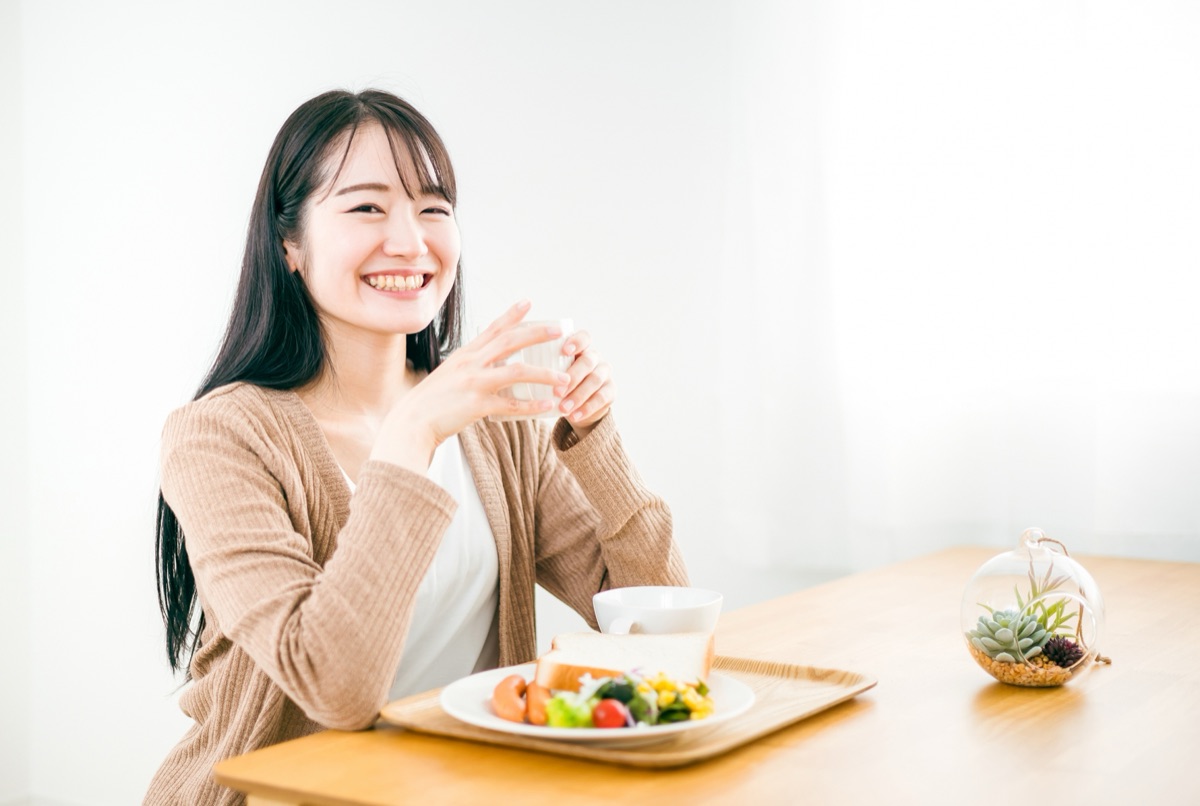 朝、温かい飲み物を手に一日を始める女性のイメージ