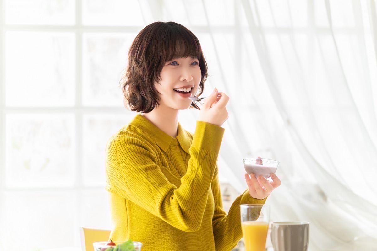食後にヨーグルトを楽しむ女性のイメージ