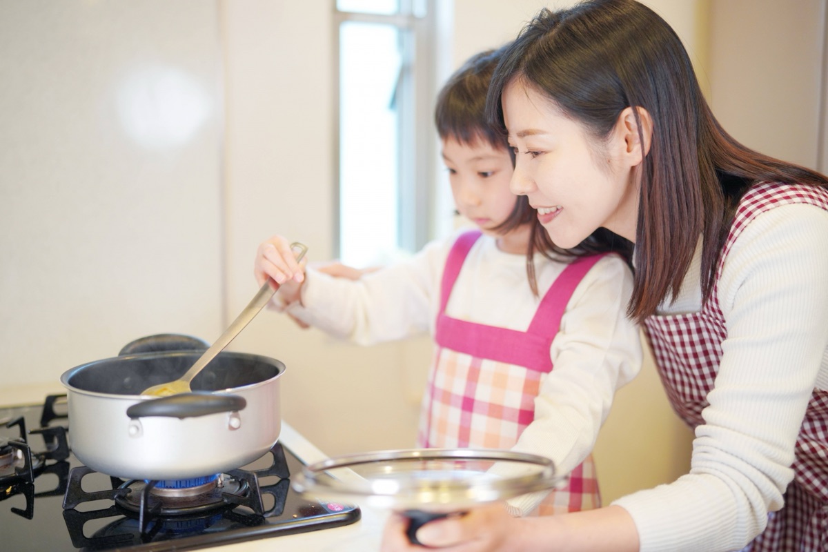 鍋の豆乳ににがりを加えて豆腐を仕込む女性の手元のイメージ