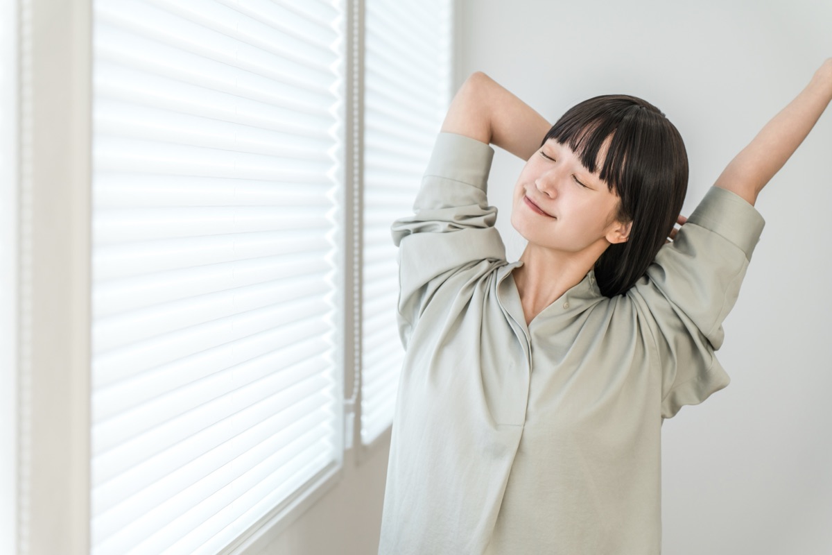 朝の光の中で深呼吸してリラックスする女性のイメージ