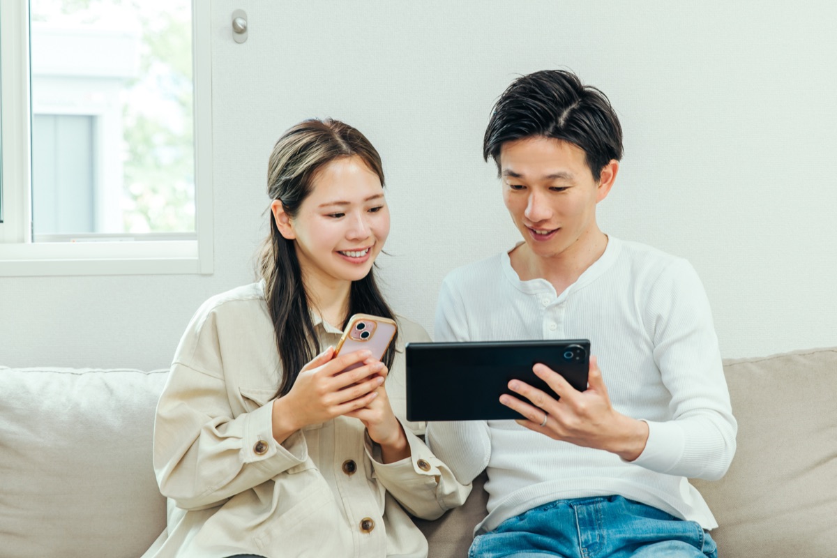 スマートフォンで価格を比較しながら検討する女性のイメージ