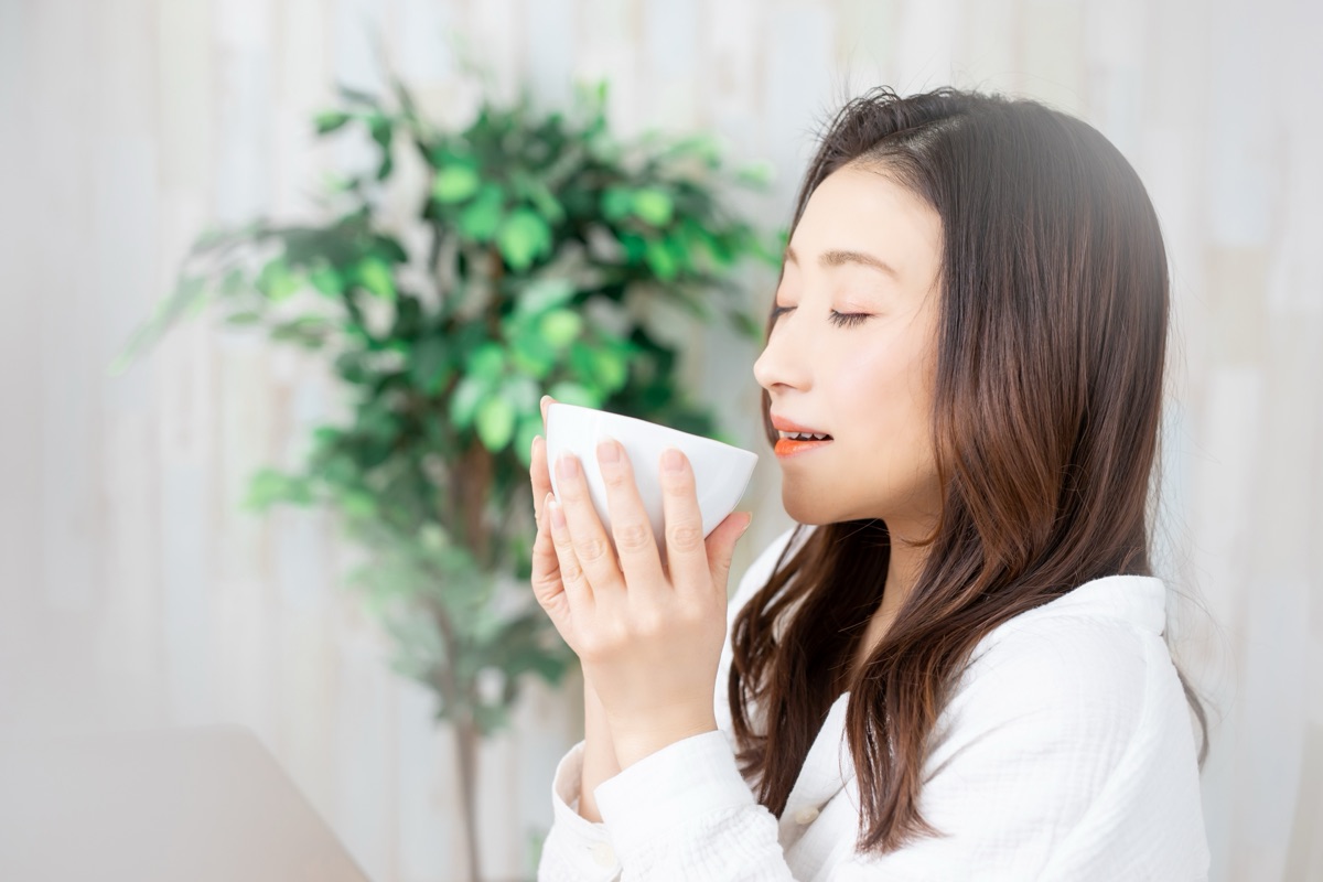 温かいスープを手にくつろぐ女性のイメージ