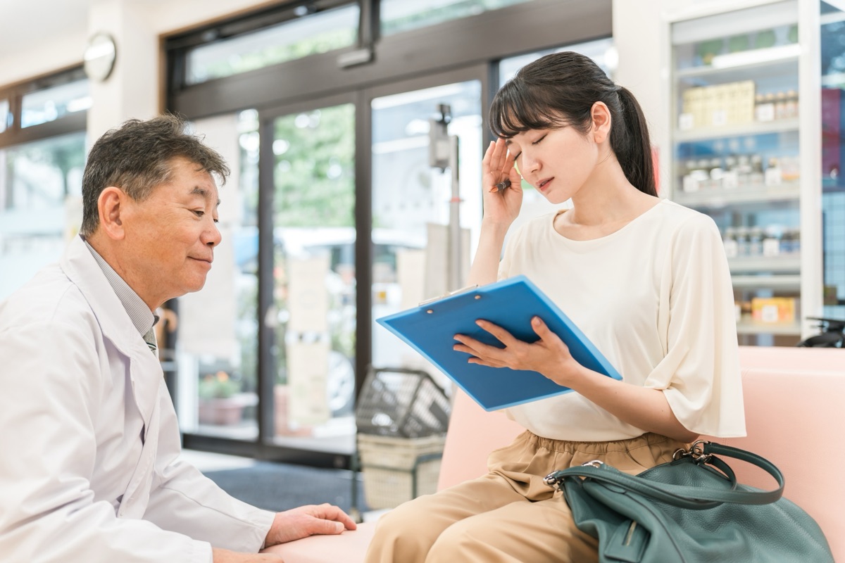 薬局のカウンターで薬剤師に相談している女性