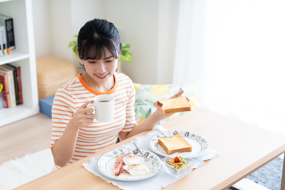 焼き上がった米粉パンを食卓で切り分けて楽しむ女性のイメージ