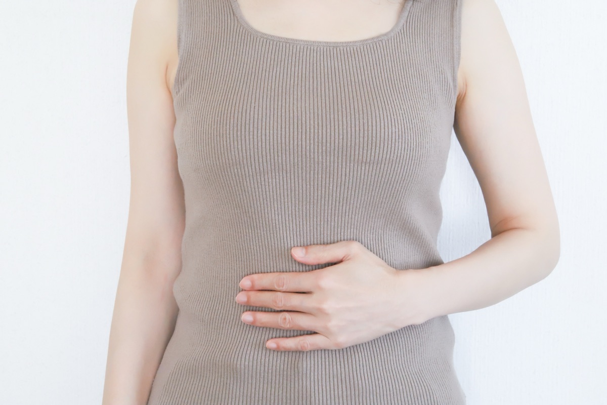 お腹の調子を気にして手を当てる女性